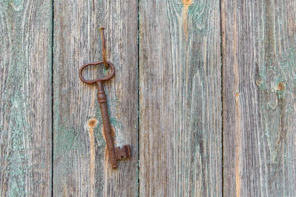 Uma chave retro de ferro velho pendurado em um prego contra a parede de uma casa de madeira rústica, o conceito de um segredo, herança, oportunidade. — Fotografia de Stock
