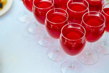 Bir sırada kırmızı içecekler, meyve suyu, şampanya ya da bir partide şarap. Yemek servisi. Masanın üzerinde beyaz bir masa örtüsü olan cam eşyalar. Bayram için açık büfe