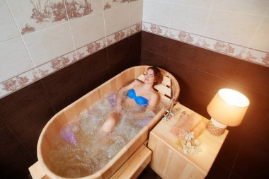 Genç bir kız çevre dostu ahşap jakuzi banyosunun tadını çıkarıyor..