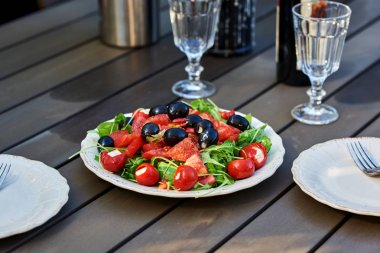 Taze salata domates, roka ve beyaz plaka ahşap arka plan üzerinde beyaz peynir ile. 