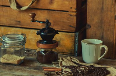 Devrilmiş çuval kahve çekirdekleri kahve fincanı, kurutulmuş portakal, anason ve koyu kahverengi dokulu arka plan üzerine tarçın ile tam.