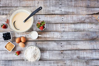 Yukarıdan vintage ahşap masa üzerinde kırsal mutfak - hamur tarifi malzemeler (yumurta, çilek, un, bilberry, süt, şeker) pasta pişirme. 