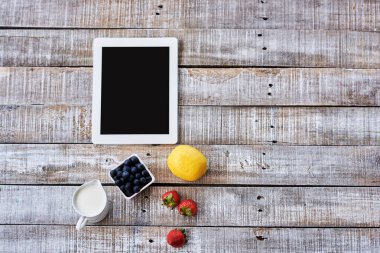  Ahşap antika masa üzerinde meyve ile tablet üstten görünüm.