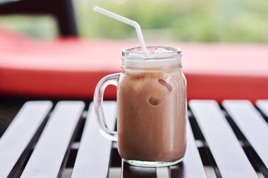 Vintage bir kupa bir ahşap masa plajda beyaz bir saman ile çikolatalı süt kapatın. Seçici odak.