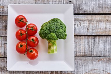 Taze organik domates, brokoli ve beyaz tabak arka plan üzerinde. Üstten görünüm. Kopya alanı.