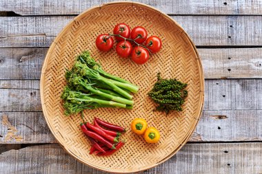 Yaratıcı sebze arka plan. Biber, biber, brokoli filizi, domates, yeşil peppercorns hasır plaka üzerinde.