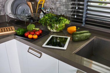 Kavramı, taze mutfak otlar, sebzeler ve tablet bilgisayar mutfak masasında yemek.