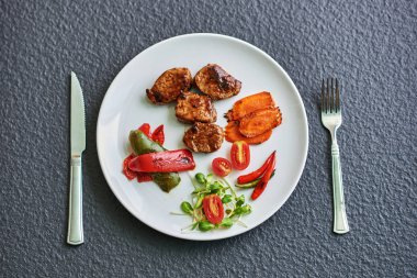 Beyaz tabakta taze sebze salatasıyla ızgara domuz eti. bir yatay görünümün üst görüntüsü.