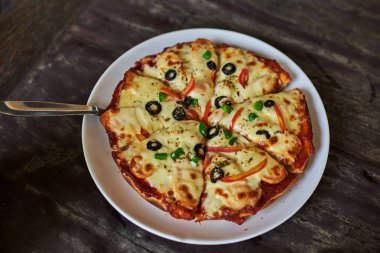 Sıcak pizza dilimi, erimiş peynirle ahşap bir masada..