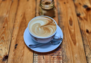 Tahta arka planda beyaz bir fincanda bir fincan kahve..