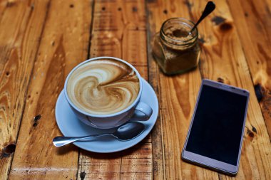 Kahve latte ve ahşap masa üstünde smartphone.