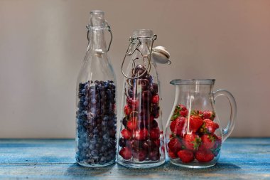 Antika ahşap masa üzerinde orada üç cam sürahi hangi taze çilek kompostosu meyve yemek için hazır mısın