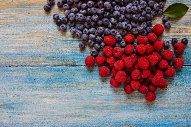 Ahşap masa yüzeyi yukarıdan görünüm vardır sadece toplanan en büyük taze ahududu ve yaban mersini