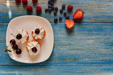 Üstten görünüm mutfak kahve evi Cook beyaz tabak çörek bazı taze yaban mersini yanındaki bir plaka üzerinde bir yumuşak ışık tereyağı krema ile servis