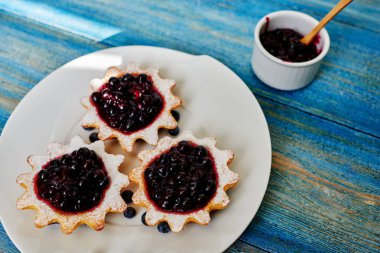 Güzel ve dikkatli bir şekilde hazırlanmış bir ev hanımı üstten görünüm tatlı hizmet, shortcrust pasta uzuvlar, kalenin orada yanındaki ev yapımı reçel ile küçük tartlets reçelli küçük bir kase