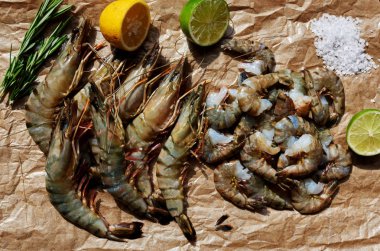 Kireç ve limon iki yarısı kapatmak için kesmek hafif kahverengi parşömen kağıt üzerine karides vardır