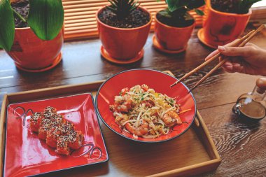 Kadın eli ulaşan Pirinç Noodle ve sushis, lezzetli ve kolay yemek için yemek çubukları ile. 