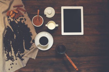 Karanlık dokusal ahşap bir masa üzerinde bir tablet bir havlu üzerinde yatıyor ve dağınık kahve çekirdekleri taze ev yapımı