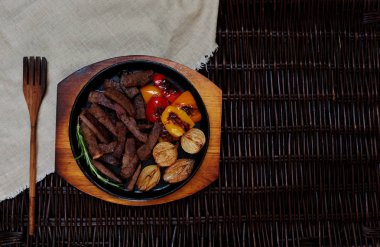 Küçük parçalar halinde, sulu ve lezzetli, kesilmiş et bir küçük dökme demir tavada sebze ile servis