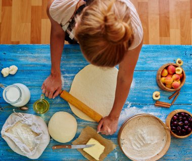 Kız Yardımcısı baker ince pasta haddelenmiş onu meyve ile bir kek yapmak