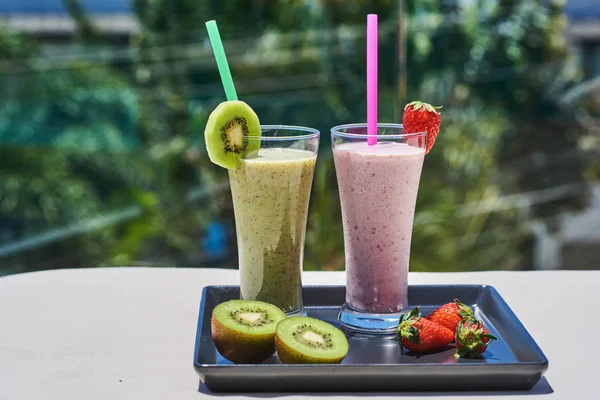 Set of fruit smoothie in glasses on tropical background.