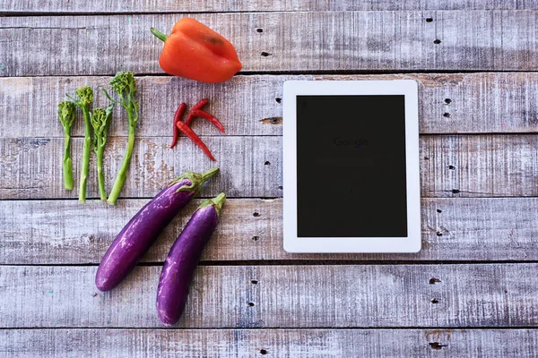 Vegetables with tablet pc iPad on vintage table. Internet online recipe book concept.