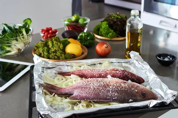 Raw ingredients. Fish and vegetables - broccoli, onions, peppers, lime and spices on the kitchen table. Cooking baked fish with vegetables.