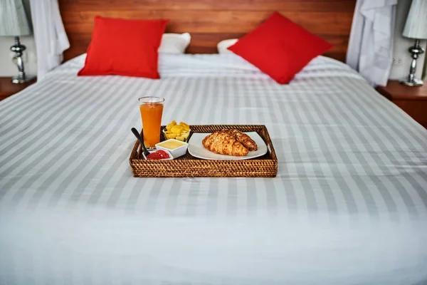 Photo of tray with breakfast food on the bed inside a bedroom.