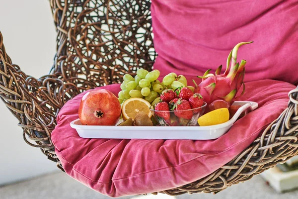 Close up of rattan rocking chair outdoors with a tray of fruit. the concept of outdoor recreation