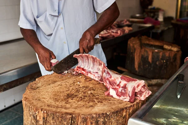 Butcher cut up pork for customers in street meat market