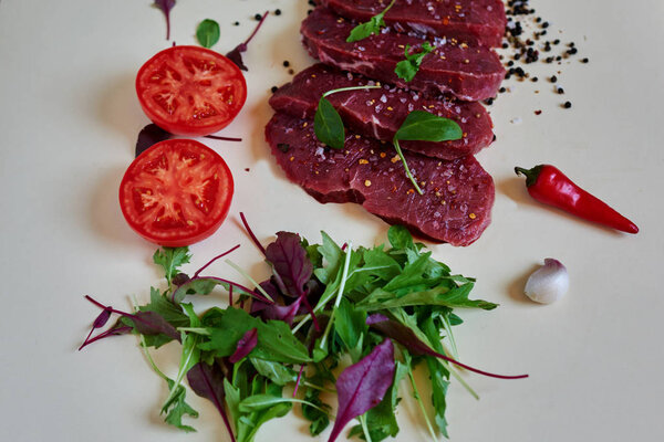 Butcher in the butcher shop to cut into portions fresh lamb, season it different spices, herbs and aromatic herbs, tomato is fresh and light salad