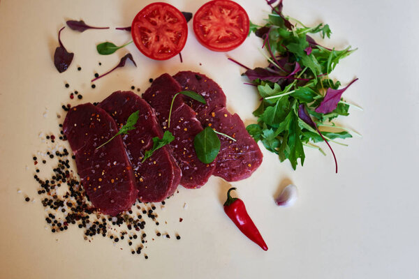 Butcher in the butcher shop to cut into portions fresh lamb, season it different spices, herbs and aromatic herbs, tomato is fresh and light salad