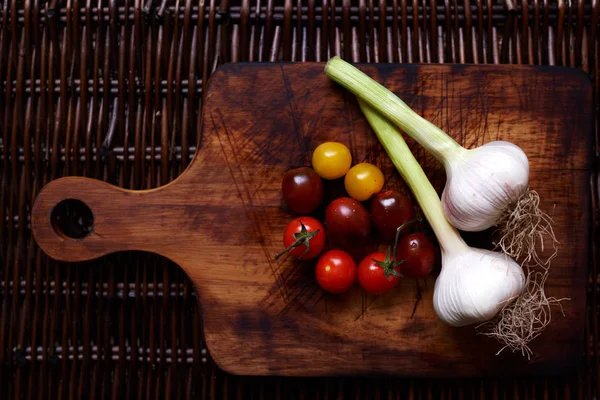 Twee Ongeschilde Knoflookteentjes Kleurrijke Cherry Tomaten Zijn Vintage Houten Snijplank — Stockfoto