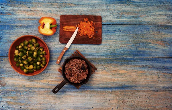 在木桌上是一个老式的小平底锅与地面牛肉 站在陶器旁边的花椰菜装饰 — 图库照片