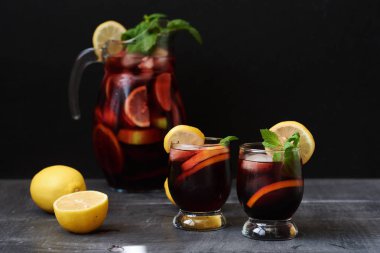 Yaz içecekler ve kokteyller. Ev yapımı sangria taze çilek, portakal, limon ve buz ile. İki bardak içinde karanlık bir vintage tablo. Uzay kopyalayın. Seçici odak.