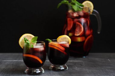 Bir sürahi ve bardak sangria, tipik bir İspanyol alkollü içki. Limon ve buz koyu arka plan üzerinde kırmızı soğuk sangria. Seçici odak.