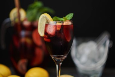 Kırmızı köpüklü şarap sangria closeup bardak koyu arka plan, narenciye dilimleri ile dekore edilmiş.