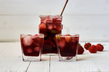 Ferahlatıcı sangria veya gözlük ve sürahi ile meyve punch. Geleneksel yaz içki içecek. Kırmızı şarap, çilek, portakal, limon ve yeşil elma. Bir ahşap rustik masaya kopya alanı ile