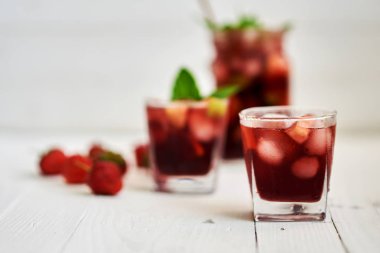 Beyaz arka plan üzerine bir bardak soğuk sangria. Yaz soğuk içecekler: Ev yapımı sangria buz küpleri ve cam ahşap zemin üzerine nane. Sangria meyve ve buz, seçici odak dilimleri ile.