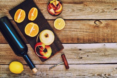 Bir şişe bir cam ve malzemeler ahşap rustik masaya eşliğinde sangria. Kırmızı şarap, portakal, limon ve elma. Geleneksel yaz içki içecek. Kopya alanı ile üstten görünüm.