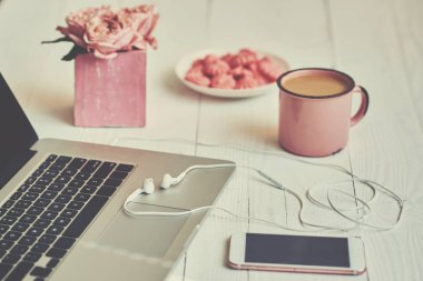 Kadınsı çalışma alanı - worksplace klavye, kahve ve çiçekler. Buket gül, fincan kahve ve eski ahşap masa üstünde laptop. Yaratıcı planlama kavramı. Üstten görünüm. Tonlu görüntü. Vintage tarzı.