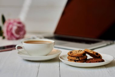 Vintage bir ahşap masa üstünde açık laptop. Taşınabilir net-kitap ve sıcak içecek fincan, kahve molası sırasında internet bağlantısı çalışmak elektronik mesafe. Kadınsı işyeri. Vintage tarzı. Seçici odak.