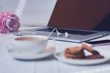 Sıcak fincan taze kahve ve çalışma masası üstünde laptop. Eve rahat ve kavram - vintage ahşap masa dizüstü bilgisayar, kahve ve bisküvi ile çalışır. Kadın zarif masaüstü. Seçici odak.