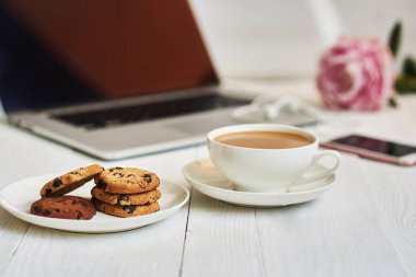 Vintage bir ahşap masa üstünde açık laptop. Taşınabilir net-kitap ve sıcak içecek fincan, kahve molası sırasında internet bağlantısı çalışmak elektronik mesafe. Kadınsı işyeri. Vintage tarzı. Seçici odak.