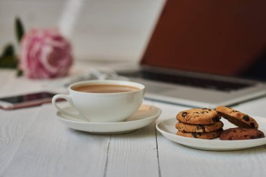 Vintage bir ahşap masa üstünde açık laptop. Taşınabilir net-kitap ve sıcak içecek fincan, kahve molası sırasında internet bağlantısı çalışmak elektronik mesafe. Kadınsı işyeri. Vintage tarzı. Seçici odak.