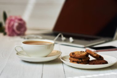 Sıcak fincan taze kahve ve çalışma masası üstünde laptop. Eve rahat ve kavram - vintage ahşap masa dizüstü bilgisayar, kahve ve bisküvi ile çalışır. Kadın zarif masaüstü. Seçici odak.