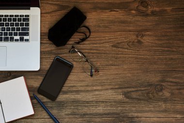 İş kavramı kopya alanı ile. Ofis resepsiyon masası. Çalışma alanı boş not defteri, dizüstü bilgisayar, gözlük smartphone ve kupa vintage ahşap masa üzerinde kahve. Vintage tarzı.