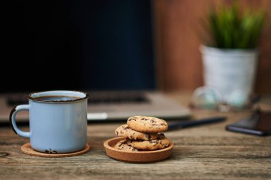 Resepsiyon ile yakından fincan kahve ve bisküvi, ofis malzemeleri ve dizüstü bilgisayar içinde belgili tanımlık geçmiş. Boş ekran bazı metin veya resim koymak için kullanılabilir. İş kavramı kopya alanı ile. Vintage tarzı