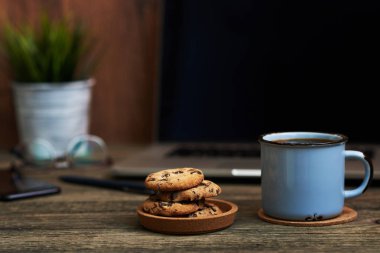 Resepsiyon ile yakından fincan kahve ve bisküvi, ofis malzemeleri ve dizüstü bilgisayar içinde belgili tanımlık geçmiş. Boş ekran bazı metin veya resim koymak için kullanılabilir. İş kavramı kopya alanı ile. Vintage tarzı