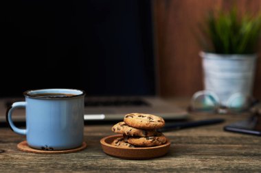 Resepsiyon ile yakından fincan kahve ve bisküvi, ofis malzemeleri ve dizüstü bilgisayar içinde belgili tanımlık geçmiş. Boş ekran bazı metin veya resim koymak için kullanılabilir. İş kavramı kopya alanı ile. Vintage tarzı